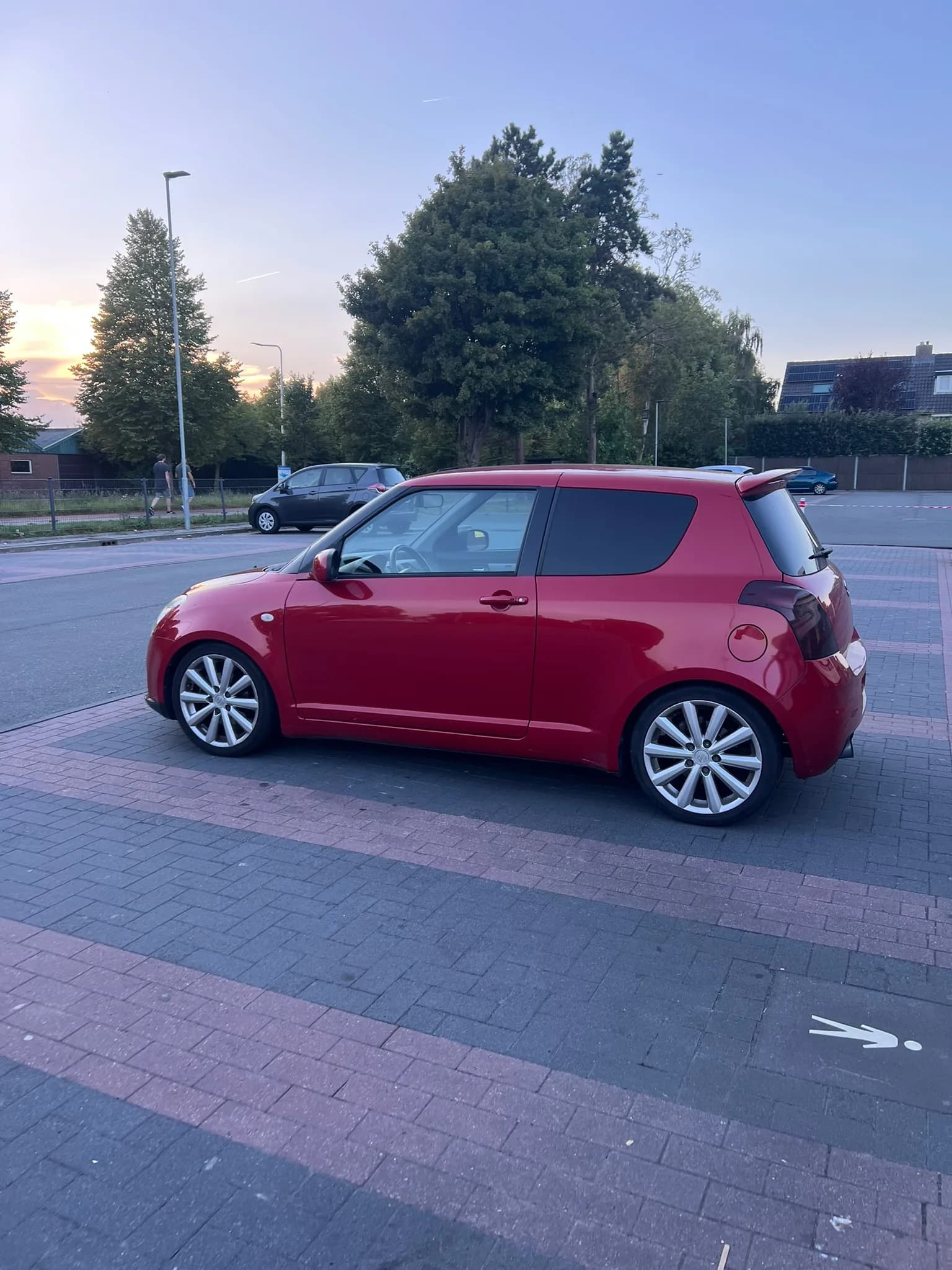 Wilberts rode Suzuki Swift Sport, schuin van opzij, op een parkeerterrein